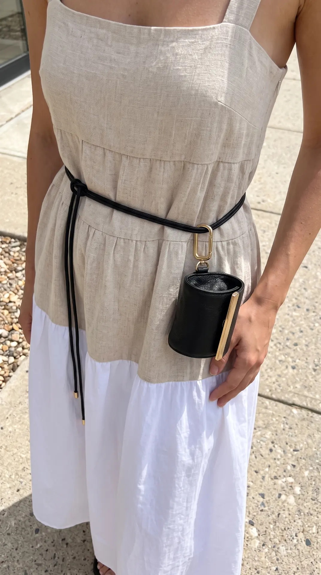The folded cliptote pouch clipped to a belt over a linen dress