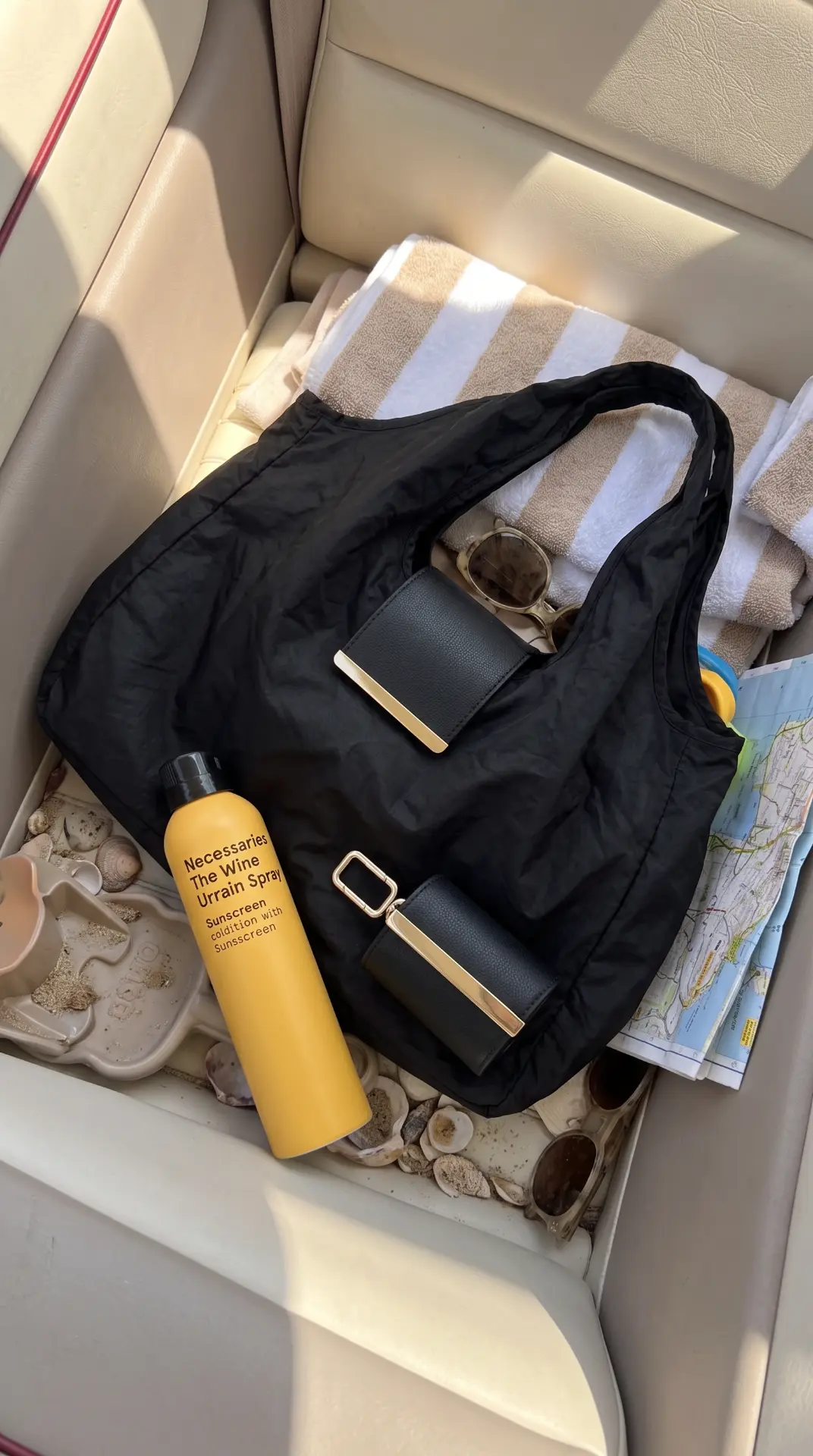 The cliptote on a car seat with a beach towel, sunscreen and sunglasses