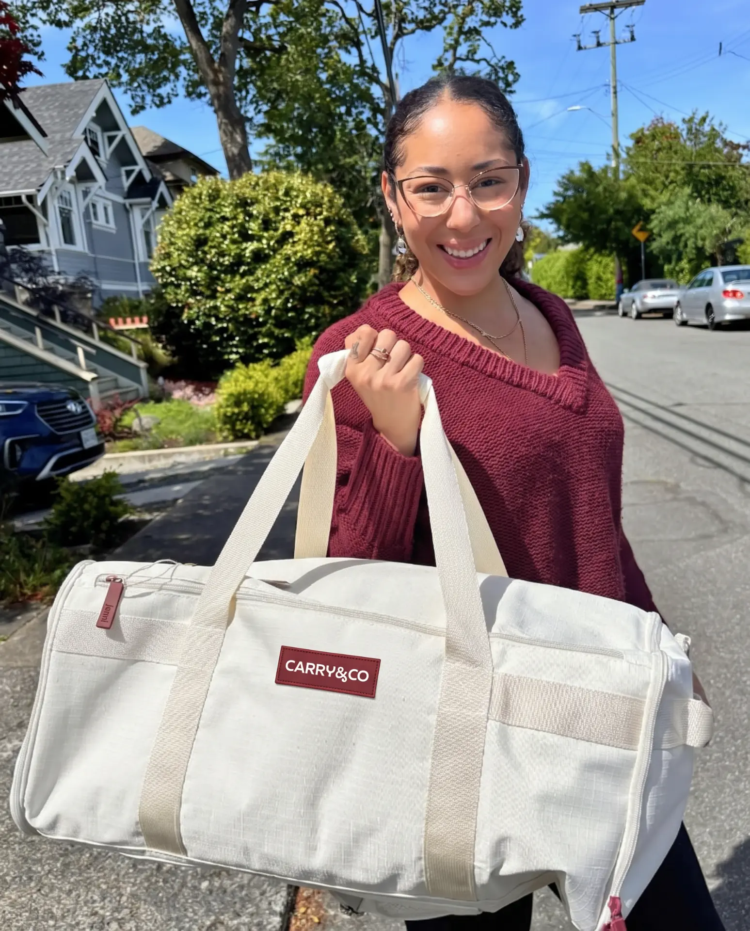 Smiling woman holding the cream Voyager bag outdoors