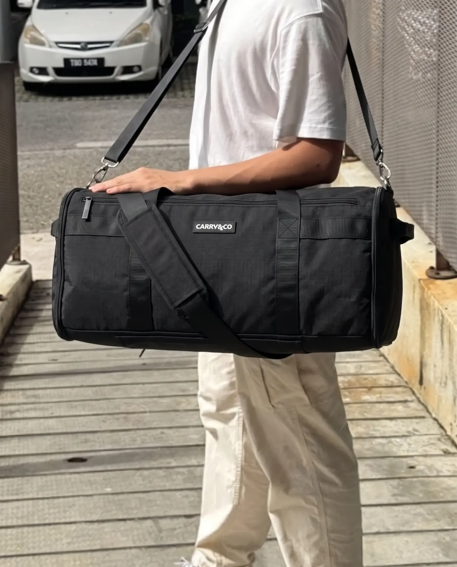 Man carrying the black Voyager duffel by its shoulder strap