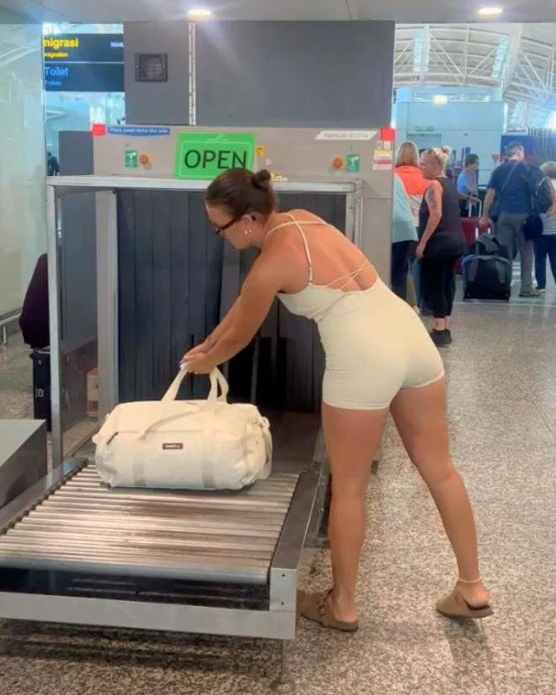 Traveller placing the cream Voyager bag on an airport security belt