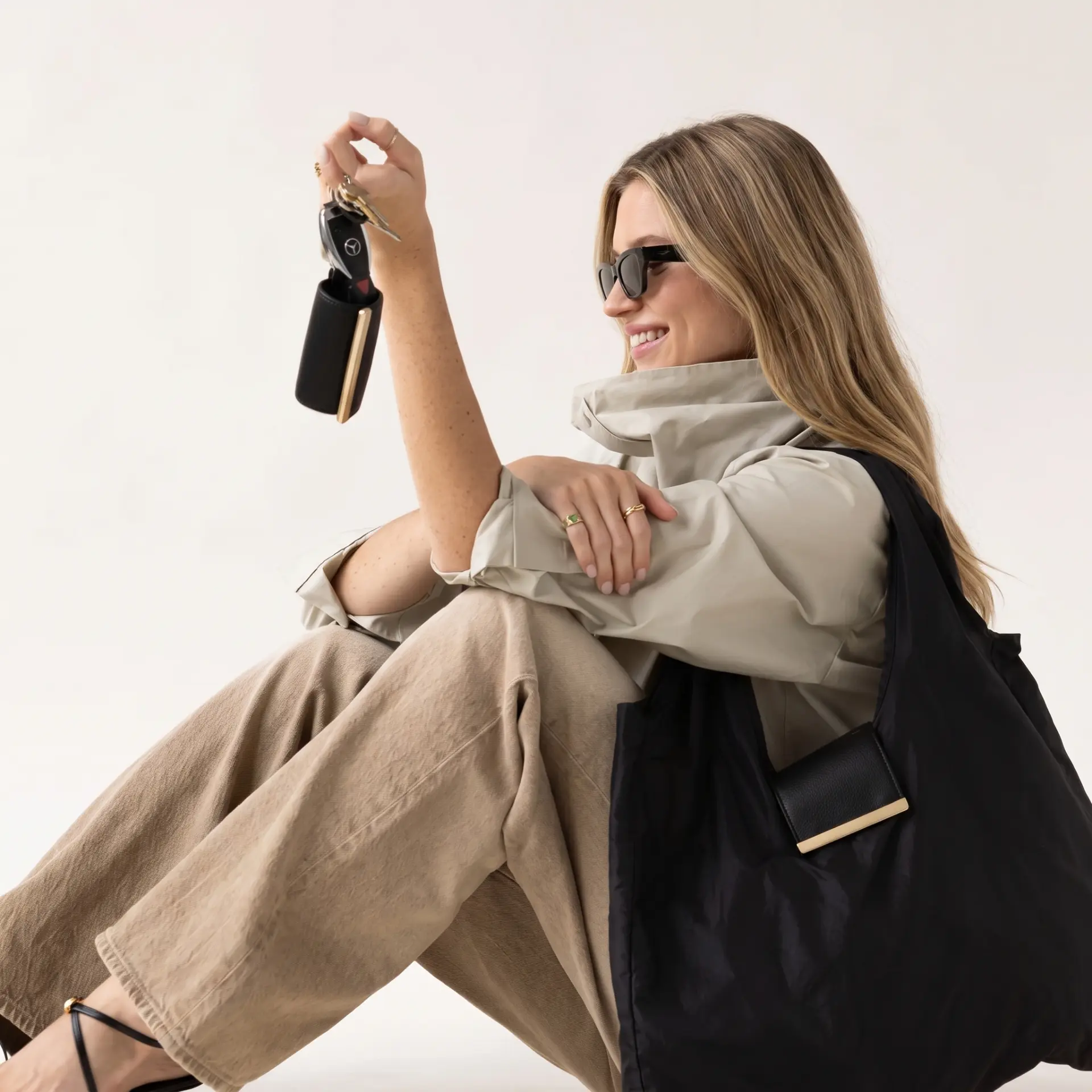 Woman seated with the cliptote on her shoulder, holding the clipped pouch on her keys